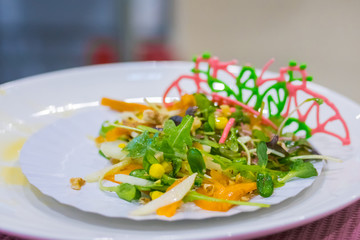 Delicious fresh exotic salad with natural ingredients for sale on white plate at cuisine of restaurant, cafe. Professional cooking, catering, cookery, gastronomy and food concept