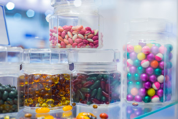 Colorful medical capsules, pills, vitamins, tablets, drugs, meds in clear glass bottle for sale at pharmacy drug store, pharmaceutical exhibition. Pharma industry, medicine and healthcare concept