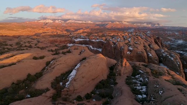 Aerial view of the rugged desert lit up at sunset looking towards the La Sal Mountains in Moab Utah.
