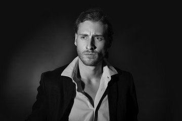 Fototapeta premium Black and white portrait of handsome businessman on dark background
