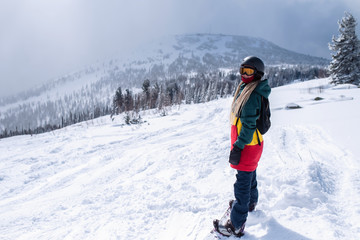 Fototapeta na wymiar Young woman snowboarder goes to the Siberian mountains.
