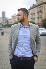 Portrait of a businessman on the street near the road of a European city. A bearded handsome man dressed stylishly. Fashionable guy hipster. Stock photos