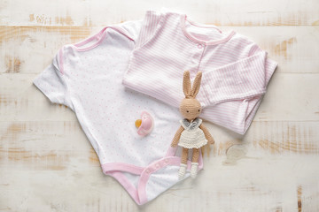 Clean baby clothes with toy and pacifier on table