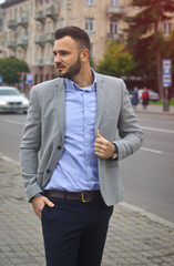 Portrait of a businessman on the street near the road of a European city. A bearded handsome man dressed stylishly. Fashionable guy hipster. Stock photos