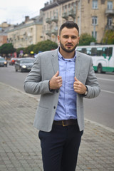 Portrait of a businessman on the street near the road of a European city. A bearded handsome man dressed stylishly. Fashionable guy hipster. Stock photos