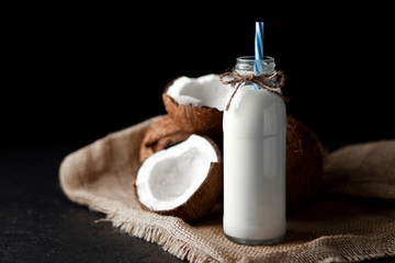 fresh coconut milk in a bottle against a dark background, coconut milkshake on a black table