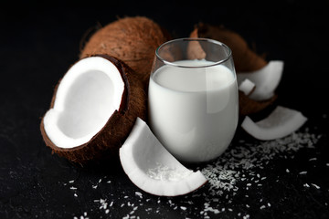 fresh coconut milk in a glass against a dark background, coconut cosmetic cream, milkshake with coconut slices