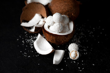 cooked coconut milk candies on a black dark background, ingredients for a dessert with coconuts, a sweet product with coconut flakes