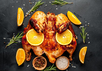 baked chicken or fried chicken with orange with spices on a stone background, top view, ready to eat