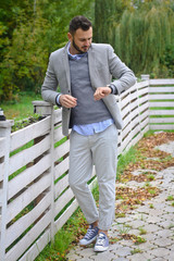 Portrait of a sexy man dressed in a suit. Fashionable guy in the autumn nature near a white wooden fence. Businessman relaxes. Skok photo for design © snb2087