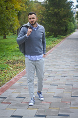 Young sexy guy strolling through the autumn, summer park. man drinking coffee, tea in the nature. European countryside. Stock Photo for design