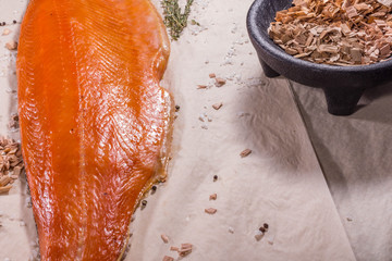 Smoked red fish lies next to smoked sawdust and tomatoes with salt. Still life