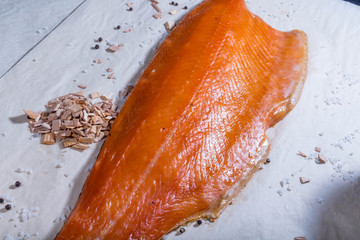 Smoked red fish lies next to smoked sawdust and tomatoes with salt. Still life