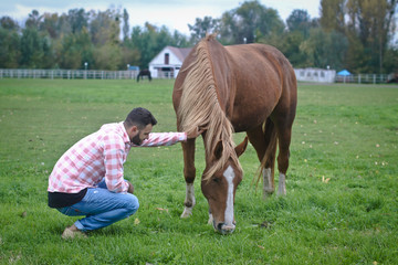 Young handsome guy Cowboy. man is a farmer in his ranch where there are many horses. Rural landscapes, countryside. Stock photos