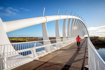 Leisure activity exercise image of a man biking across a bridge. With beautiful lens flare effect.