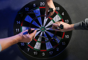 Obraz premium People taking darts out of dartboard