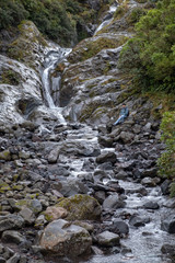 A hiker rests on the edge of and admire Wilkies Pools, Mount Egmont, New Zealand.