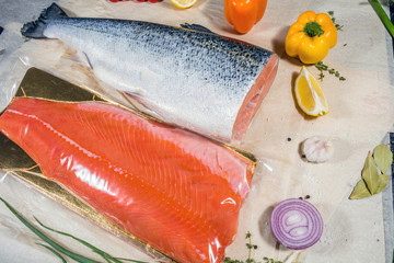 Salmon fish in a large piece and sealed around vegetables pepper onion tomatoes and lemon fruits