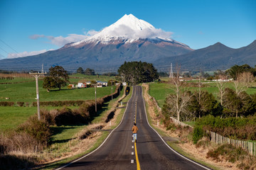 Fototapeta premium Determined person runs on a straight road toward snow mountain