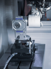 Industrial robot arm loading workpiece to CNC lathe sliding headstock. Industrial metalworking machinery