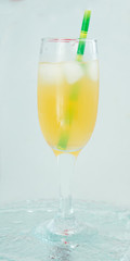 champagne glass with cocktail, juice with ice green straw on water light background