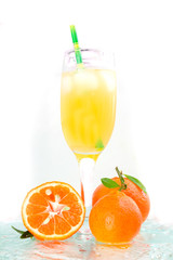 champagne glass with cocktail, juice with ice tangerines with ice cubes, green tubule on the water light background