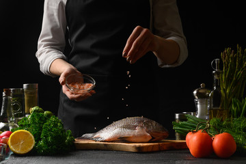The chef cooks fish, sprinkles with sea salt, freeze in motion, seafood, gastronomy, sale of fresh fish, fish market. Homemade Fish Recipes