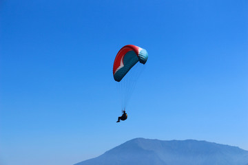 a paraglider flying in blue sky landscape in Indonesia
