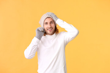 Handsome man in winter clothes on color background