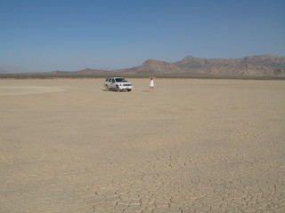 Auto steht in der Wüste mit Frau im weißen Kleid