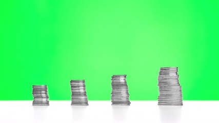 Four coin stacks on green screen, representing financial quarters with increasing and decreasing size - stop motion loop. Positive financial report concept.