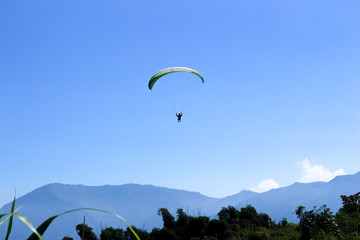 paraglider flying in blue sky on valleys landscape in Indonesia