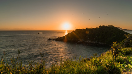 Obraz premium Pássaros voando com o sol nascendo nas montanhas sobre o mar