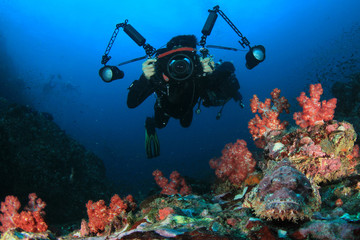 Underwater photographer scuba dives on coral reef 