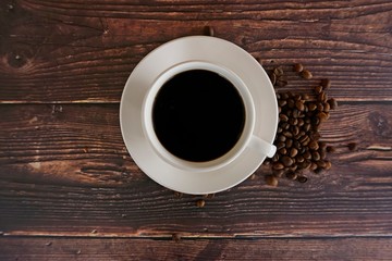 cup of coffee with beans on wooden table