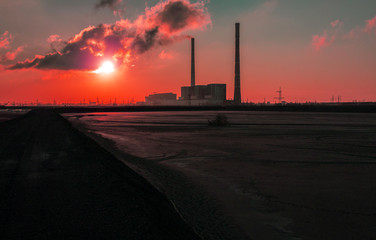 smoking chimney of a factory against fiery orange sunset. colorful and speckled  clouds.