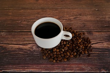 cup of coffee with beans on wooden table