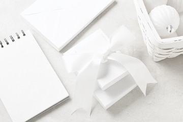 Flat Lay closeup of White Christmas Presents with a basket of ornaments, a note pad and envelopes.