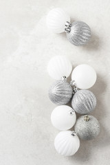 Fototapeta na wymiar Silver and white Christmas Tree Balls on a light mottled gray surface. Vertical with copy space.