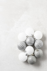 A group of silver and white Christmas Tree Ornaments on a light gray surface. Vertical with copy space.