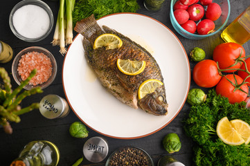 Grilled fish with fresh vegetables, on a wooden black background. I also eat healthy food. Seafood, Eastern or European cuisine.
