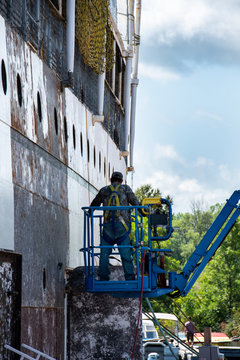 Men working painting the side of a ship