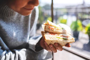 Photo sur Plexiglas Snack Image en gros plan d& 39 une femme tenant et mangeant un sandwich de blé entier le matin