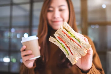 Papier Peint photo Lavable Snack Closeup image of an asian woman holding whole wheat sandwich and coffee cup
