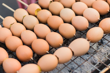 Grilled eggs skewered on a metal grill on a charcoal stove.