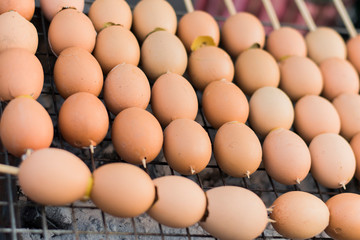Grilled eggs skewered on a metal grill on a charcoal stove.
