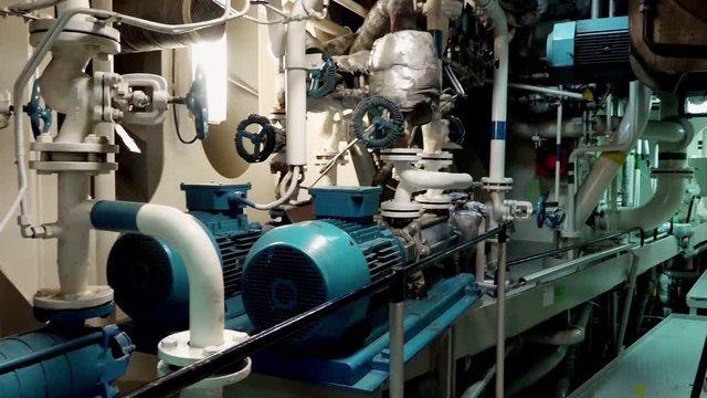 multiple complicated pipelines with valves and painted in blue oil filters extend across engine room in tanker close view