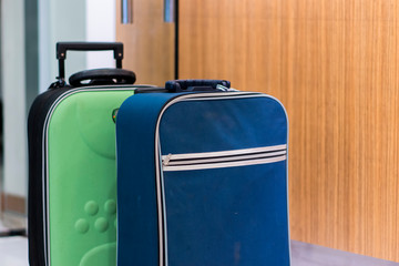 Large suitcases, blue and green, are placed near each other on the ground.