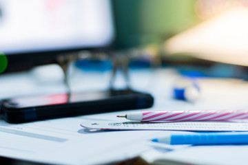 Focus the pen and the ruler placed on the white paper and blur other devices.  And blur the background