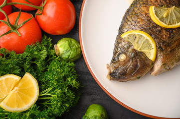 Stewed fish with lemons and fresh vegetables. Delicious and healthy food.